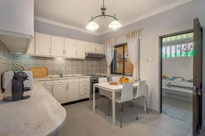 a kitchen with a white table and white cabinets at Bambus House Blue in Quarteira