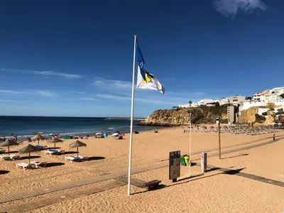 a blue and white flag on a sandy beach at Deluxe apartment in Albufeira old town, 200m walk to beach, pool parking in Albufeira