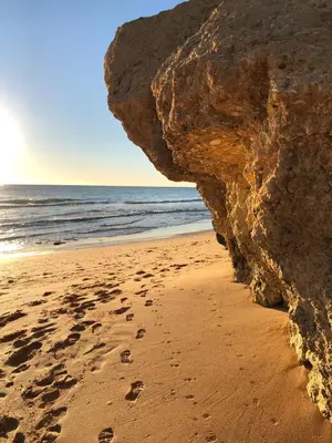 a rock on a beach with footprints in the sand at Deluxe apartment in Albufeira old town, 200m walk to beach, pool parking in Albufeira