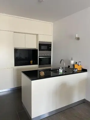 a kitchen with white cabinets and a black counter top at Deluxe apartment in Albufeira old town, 200m walk to beach, pool parking in Albufeira