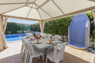 a table and chairs under a large umbrella on a patio at Villa Tulipa in Albufeira