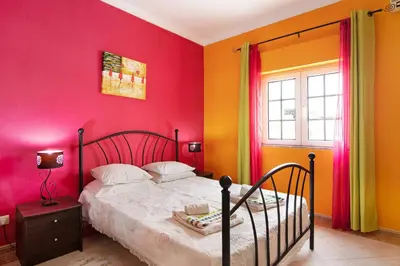 a bedroom with pink and orange walls and a bed at T2 Anastácio com vista Piscina in Olhos de Água