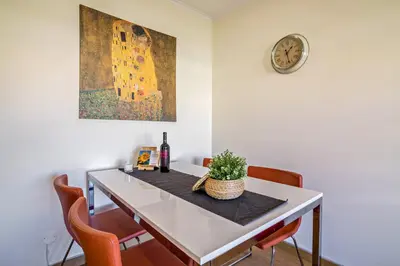 a dining room table with a bottle of wine and a clock at Vilamoura Boutique Apartment in Quarteira
