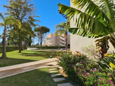 a park with palm trees and flowers and a building at Protea 214-CleverDetails, Located in heart of Vilamoura Sleeps 2 adults, 1child in Vilamoura