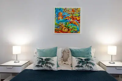 a bedroom with a bed with pillows and a painting on the wall at Palmeira Galé in Galé