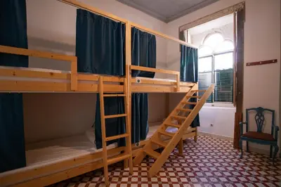 a small room with a bunk bed with a ladder at Tilia Hostel in Faro