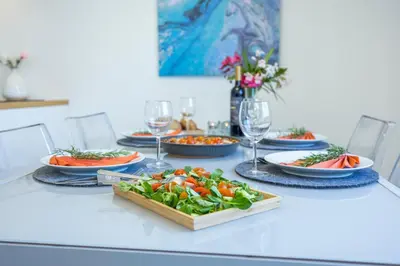 a table with plates of food and wine glasses at Stylish Algarve Apartment with Spacious Terrace & Sea Views in Quarteira