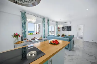 a kitchen and living room with a blue couch at Stylish Algarve Apartment with Spacious Terrace & Sea Views in Quarteira
