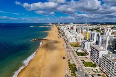 a view of a beach with buildings and the ocean at Stylish Algarve Apartment with Spacious Terrace & Sea Views in Quarteira