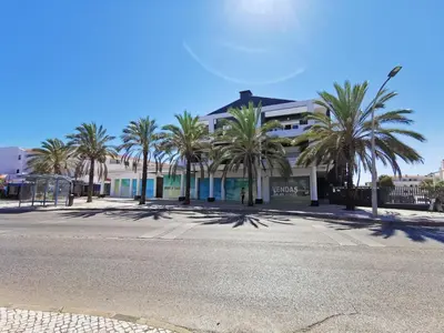 a building with palm trees in front of a street at AlbufeiraMar Beach Apartment in Albufeira