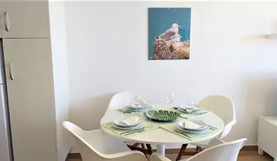 a white dining room with a white table and chairs at T1 Mira Praia 7 - Remodelado, Ar-Condicionado, Vista Mar, Wifi in Quarteira