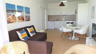 a living room with a couch and a table with chairs at T1 Mira Praia 7 - Remodelado, Ar-Condicionado, Vista Mar, Wifi in Quarteira