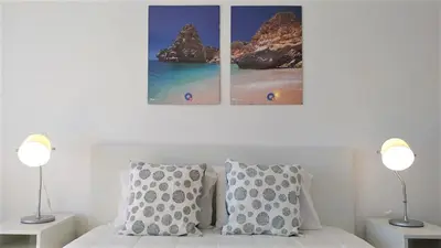 a bedroom with three pictures above a bed with two lamps at T1 Mira Praia 7 - Remodelado, Ar-Condicionado, Vista Mar, Wifi in Quarteira