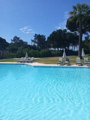 a large swimming pool with chairs and a beach at Quinta do Lago Villa and Golf in Quinta do Lago