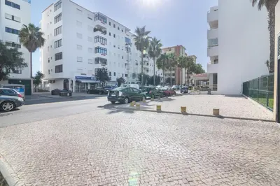 a cobblestone street in a city with buildings and cars at Regueiró Quarteira Beach Apartment in Quarteira