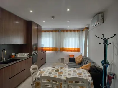 a kitchen and living room with a table and a couch at Regueiró Quarteira Beach Apartment in Quarteira