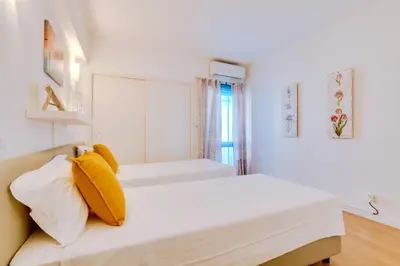 a white bedroom with two beds and a window at AL - Apartamento 1021 Impervilla in Quarteira