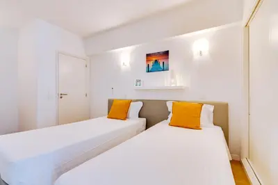 two beds in a white room with orange pillows at AL - Apartamento 1021 Impervilla in Quarteira