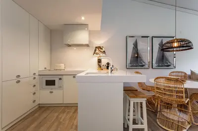 a kitchen with white cabinets and a counter with chairs at M&M Home in Quinta do Lago
