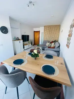 a dining room table with chairs and a living room at Apartamento Varandas do Mar in Albufeira