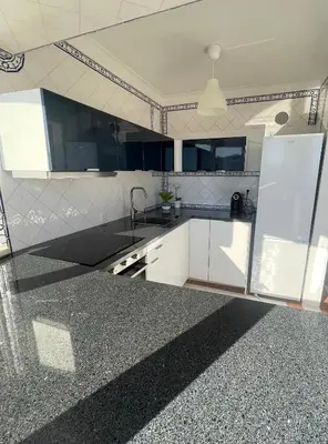 a kitchen with white cabinets and a black counter top at Apartamento Varandas do Mar in Albufeira