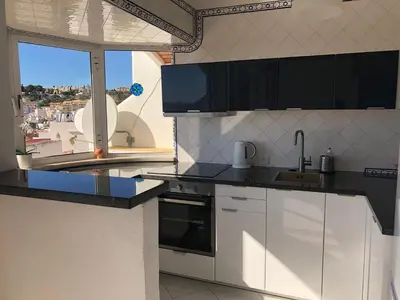a kitchen with white cabinets and a large window at Apartamento Varandas do Mar in Albufeira