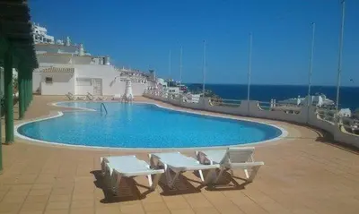 a swimming pool on a cruise ship with two benches at Apartamento Varandas do Mar in Albufeira