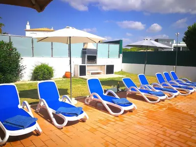a row of blue and white chairs and an umbrella at Heated Pool 6 Bedroom Private Villa in Center of Olhos de Água in Albufeira
