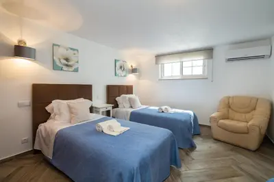 a hotel room with two beds and a chair at Heated Pool 6 Bedroom Private Villa in Center of Olhos de Água in Albufeira