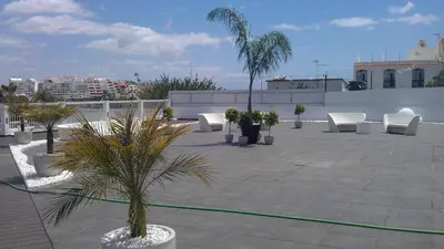 a patio with white chairs and palm trees on a building at Bay View Old Town Apartments in Albufeira