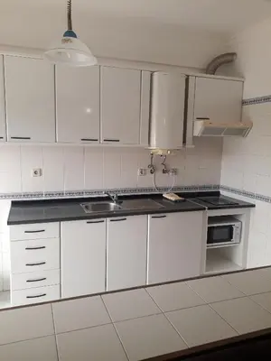 a white kitchen with white cabinets and a sink at cantinho do mar in Albufeira