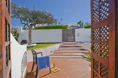 a patio with a white fence and a blue chair at Villa Dela by Villa Plus in Albufeira