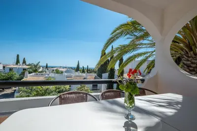 a vase with flowers sitting on a table on a balcony at Carolina Sea Apartment in Albufeira