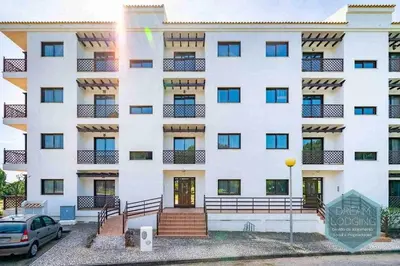 a white building with a car parked in front of it at Falésia Park - Dream Lodging in Albufeira
