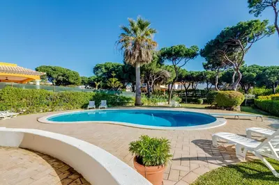 a swimming pool with two chairs and a palm tree at LovelyStay - Villa Mimi in Vilamoura