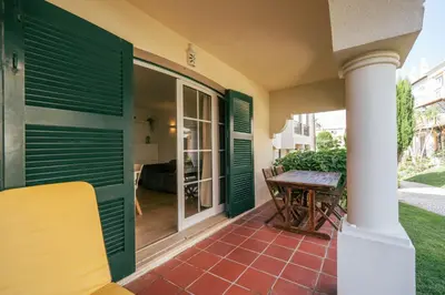 a porch with green shutters and a wooden table at Sweet Old Village in Quarteira