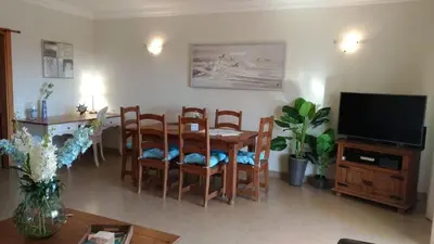 a living room with a table and chairs and a television at J&J Home T2 next to Pinhal Velho, Terraces of Pinhal, Vilamoura in Quarteira
