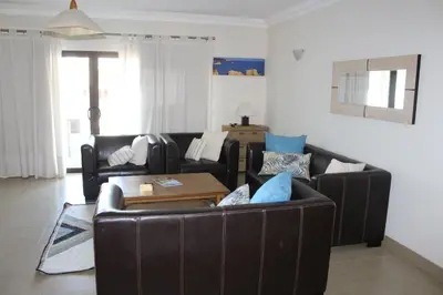 a living room with a leather couch and a table at J&J Home T2 next to Pinhal Velho, Terraces of Pinhal, Vilamoura in Quarteira