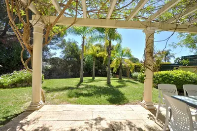 a yard with a tree and a house at A stylish villa with a private pool, short drive from the centre, free AC Wifi in Quarteira