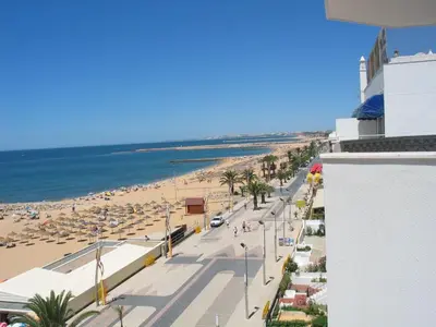 a view of a beach with people and umbrellas at Quarteira, Algarve - Seaview - Horizonte Mar in Quarteira