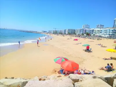 a group of people laying on a beach with umbrellas at T1 PonteMira 6 50M PRAIA VISTA MAR in Quarteira