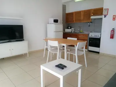 a kitchen with a wooden table and white chairs at T1 Praiamar 4 Vista Magnifica in Quarteira