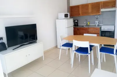 a kitchen with a wooden table and blue chairs at T1 Praiamar 4 Vista Magnifica in Quarteira