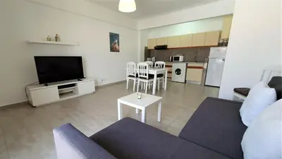 a living room with a couch and a tv and a kitchen at T1 Dunas 7 - Aconchegante, Wifi, 150mt Praia in Quarteira