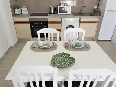 a kitchen with a white table and chairs and a sink at T1 Dunas 7 - Aconchegante, Wifi, 150mt Praia in Quarteira
