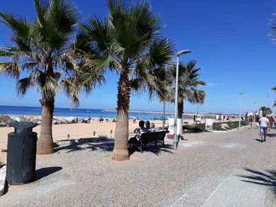 two people sitting on a bench next to the beach at T1 Dunas 7 - Aconchegante, Wifi, 150mt Praia in Quarteira