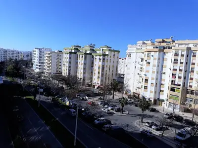 a city with tall buildings and a parking lot with cars at Torre 6- Vista Cidade, Aconchegante, 80mt Praia, Wifi in Quarteira