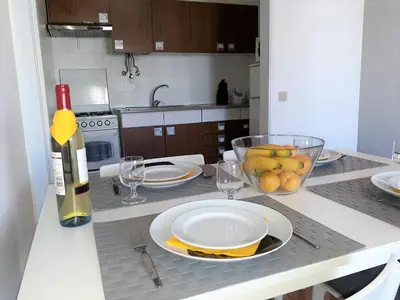 a kitchen with a table with plates and a bottle of wine at Torre 6- Vista Cidade, Aconchegante, 80mt Praia, Wifi in Quarteira