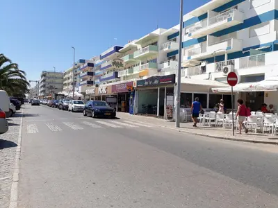 a street with cars parked on the side of a building at Torre 6- Vista Cidade, Aconchegante, 80mt Praia, Wifi in Quarteira
