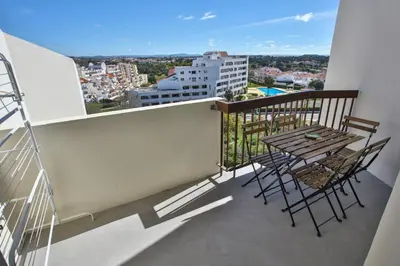 a balcony with a table and chairs on a building at Go4Portugal - Vilamagna - Luxe Condo with Pool, Airco and Seaview Balcony in Albufeira